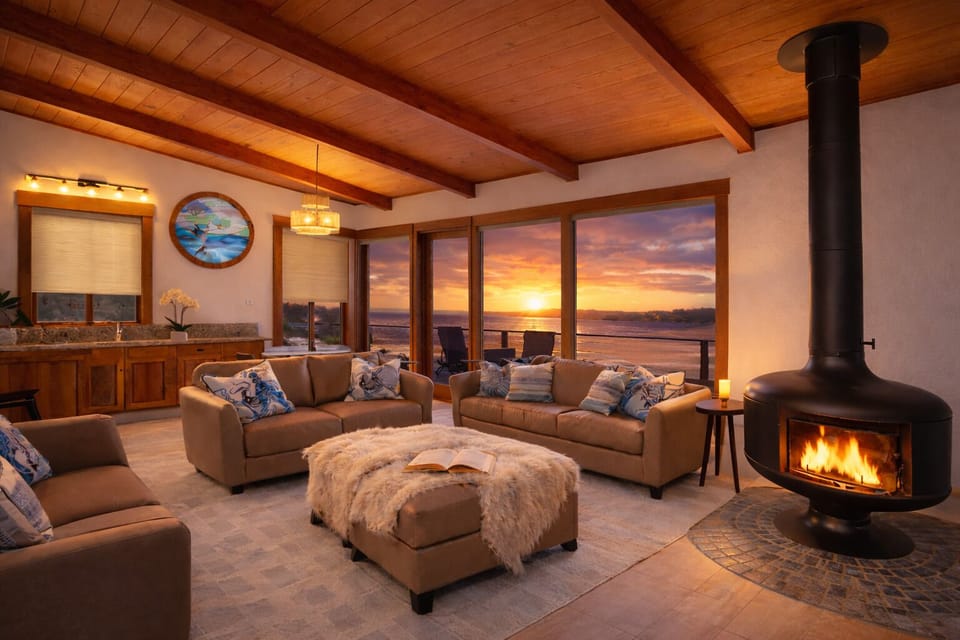 Oceanfront living room glowing at sunset with fireplace