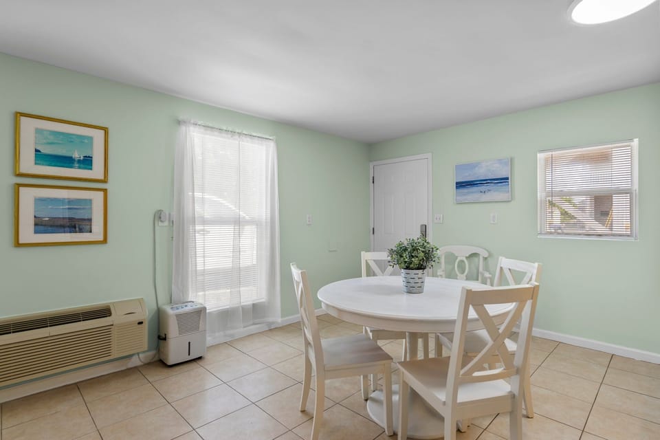 Gather around your bright dining table where coastal artwork and soothing mint walls create the perfect backdrop for memorable meals.