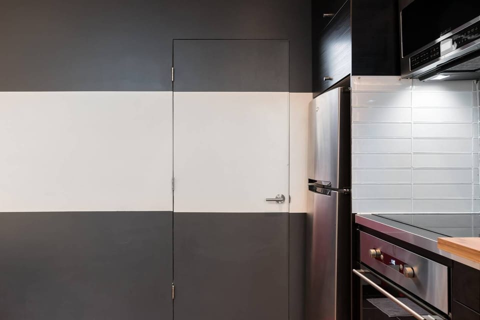 The bathroom is behind the door next to the kitchen