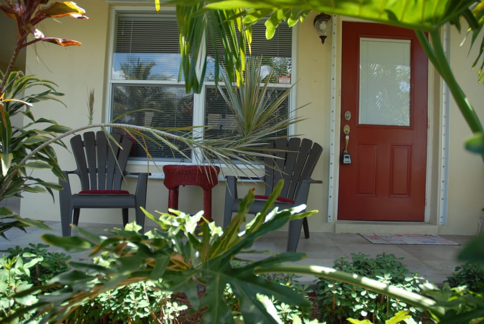 Front porch enveloped in tropical plants, cascading water & wind chimes