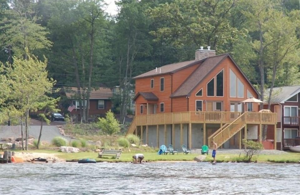View of house from lake.  Wrap around deck and large open space next to home