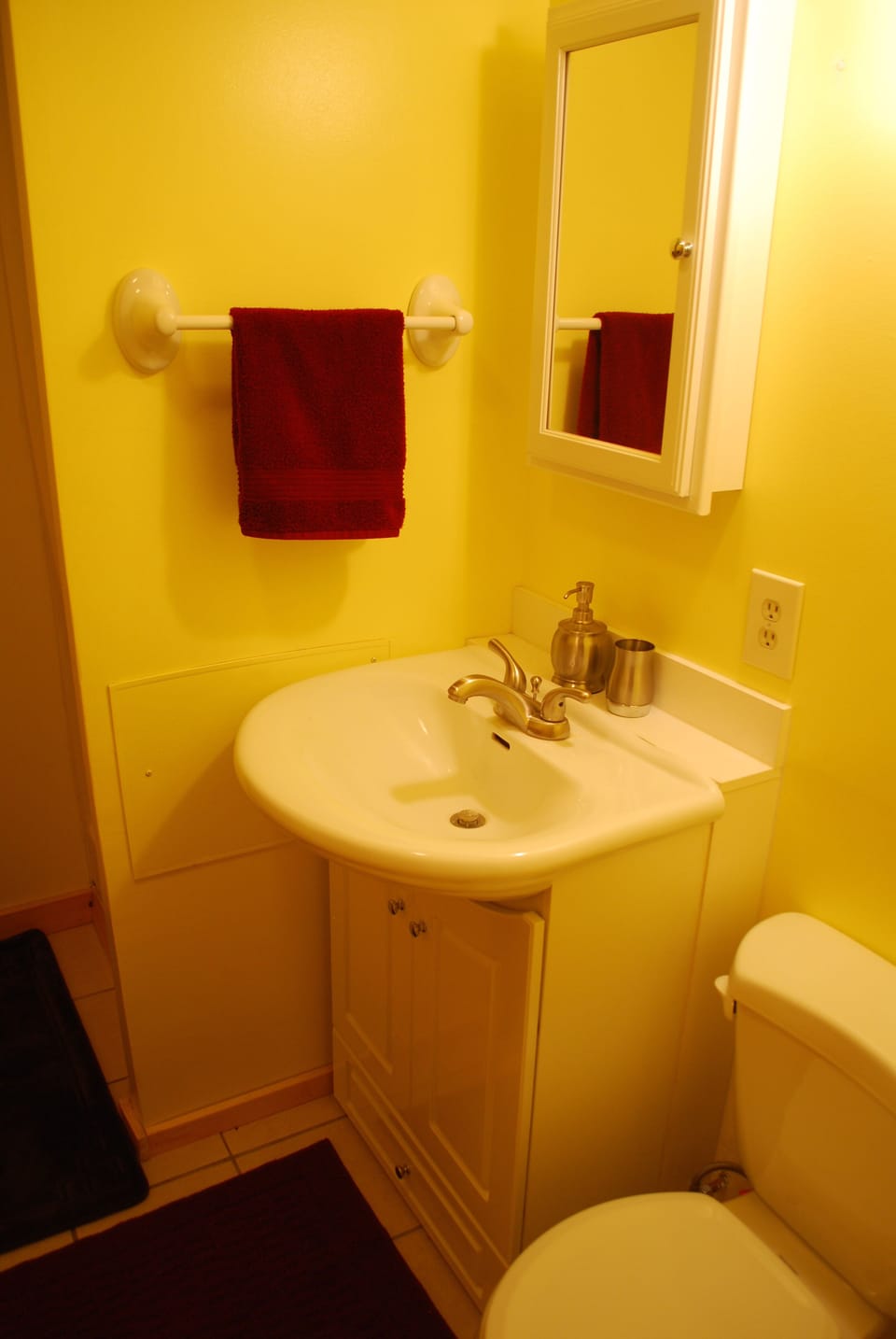 Small bathroom with toilet, sink, and small stall shower.