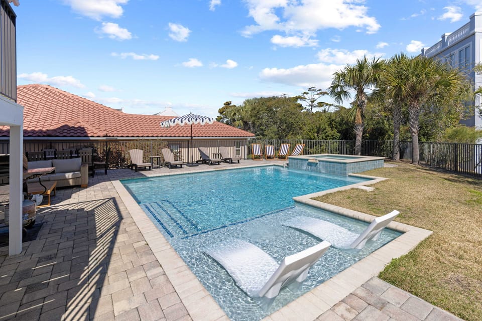 Dive into your private oasis with sparkling pool, bubbling spa, and loungers surrounded by tropical palms and sunny skies.