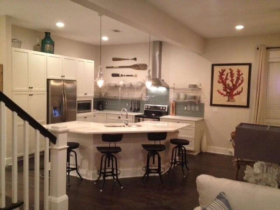 Open, fully stocked kitchen with island over looking dining, and living room