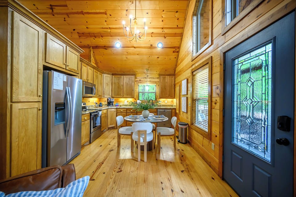 Enjoy cooking and dining in this warm, sunlit space with rustic wood finishes, modern appliances, and an intimate table perfect for your morning coffee or evening meals.