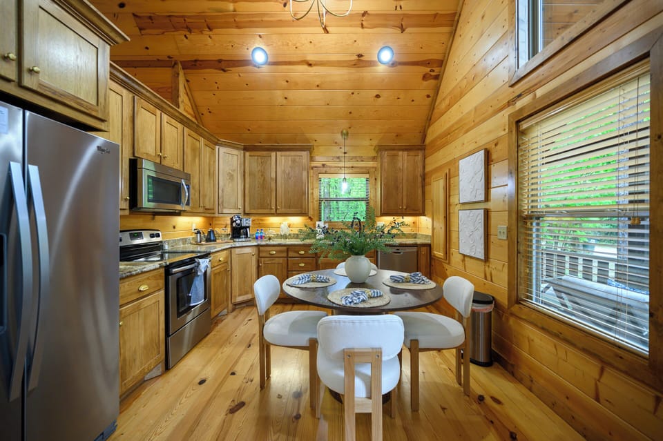 Gather around the beautifully set table in your rustic-chic kitchen, where warm pine walls and modern appliances create the perfect spot for home-cooked meals and morning coffee together.