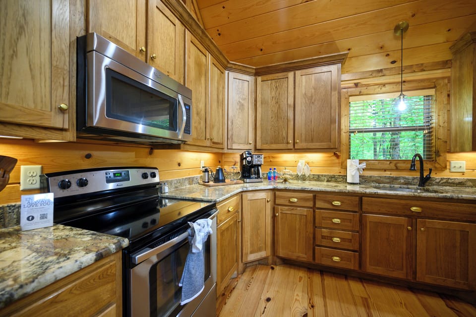 Warm wood surrounds you in this fully equipped kitchen, with granite counters, modern appliances, and views of nature just beyond your window—a perfect space to prepare your favorite meals.