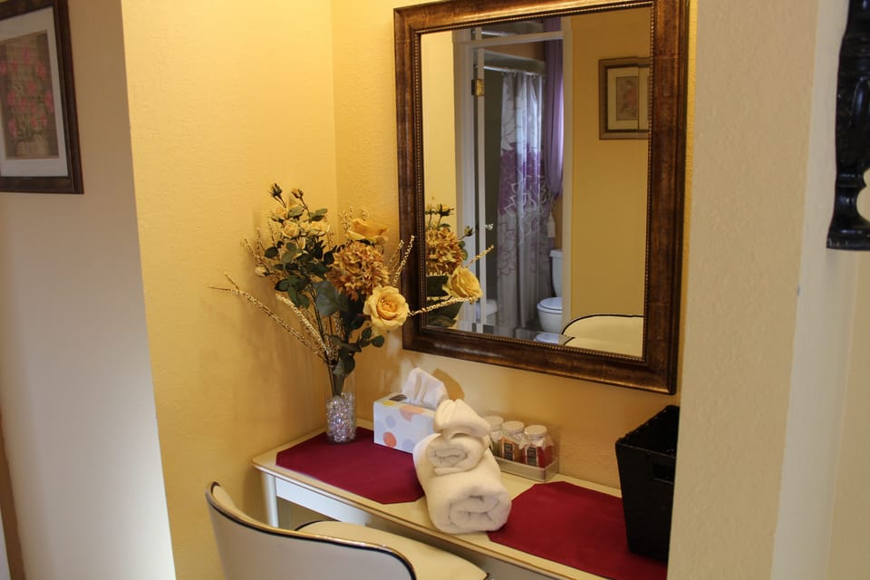 Elegant vanity area with mirror, floral arrangement, and seating