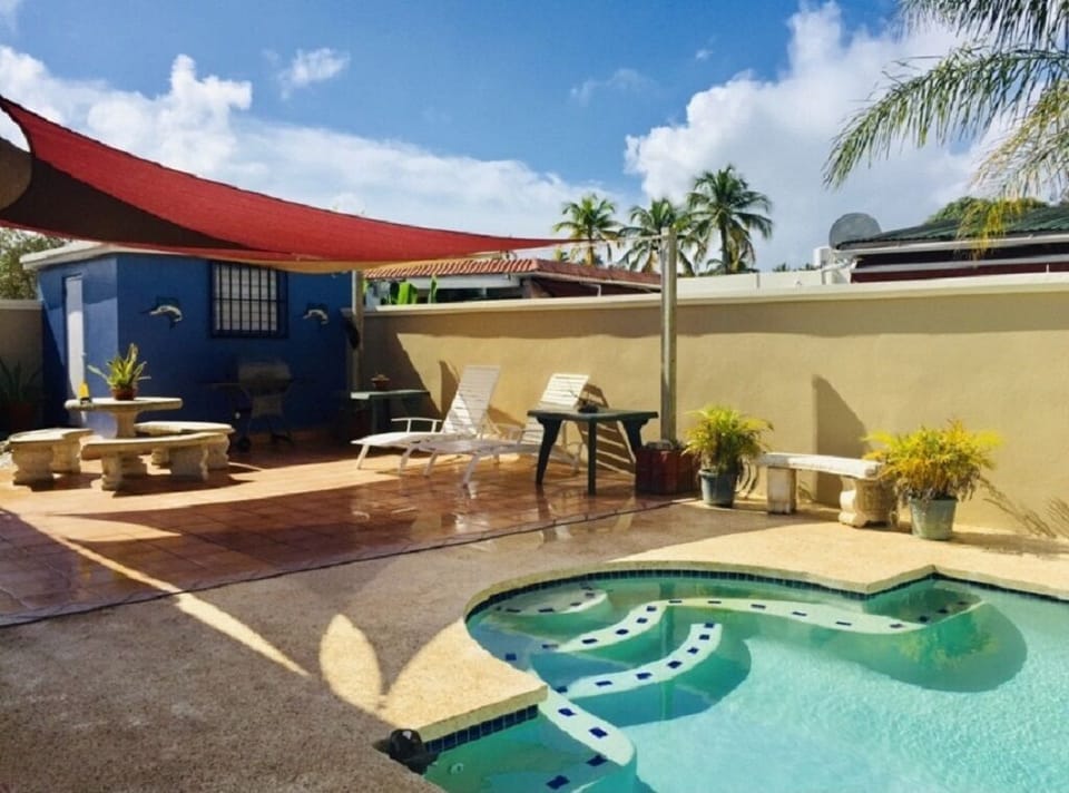 Private pool with BBQ, chairs, and tables.