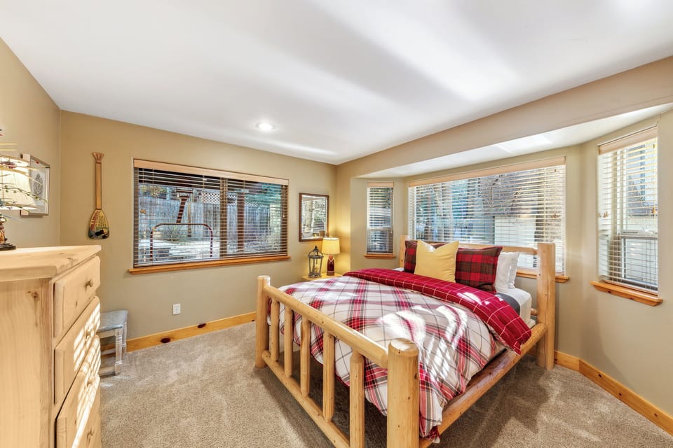 Cozy up in your charming bedroom with rustic log furnishings and festive plaid linens that create the perfect mountain retreat atmosphere.
