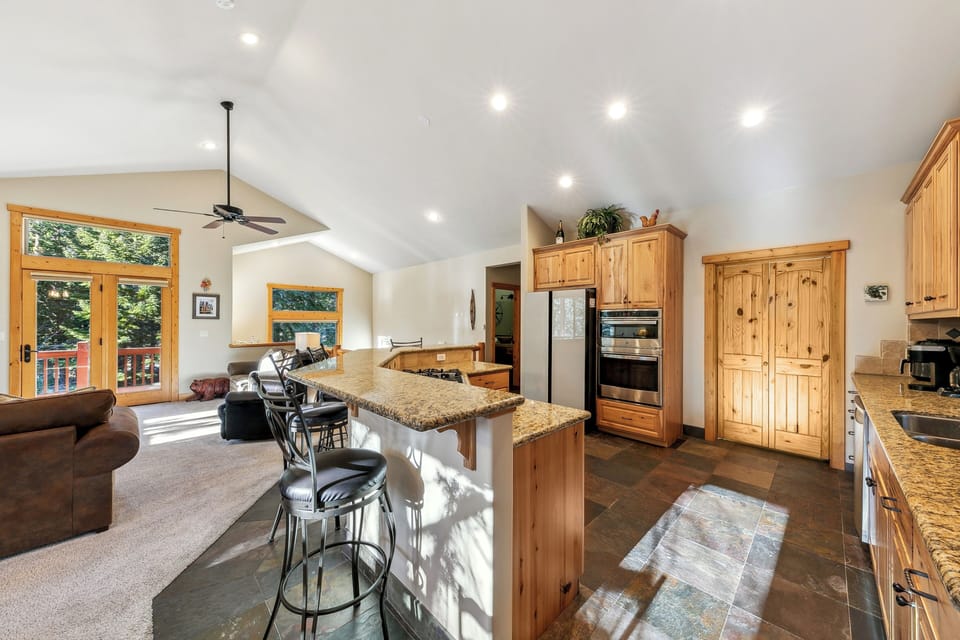 Your spacious open kitchen flows seamlessly into the living area, featuring warm wood cabinetry and granite countertops perfect for cooking together.