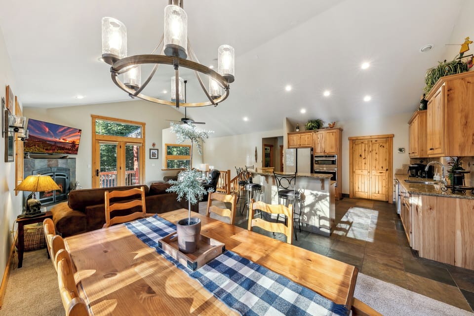 Your open-concept living space features warm wood accents, vaulted ceilings, and a stunning chandelier creating the perfect mountain retreat atmosphere.