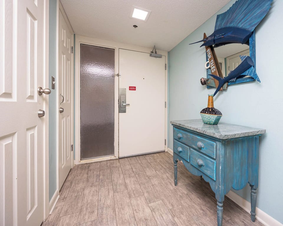 Step into a welcoming entryway featuring coastal decor, a charming blue console table, and soft lighting for a warm arrival