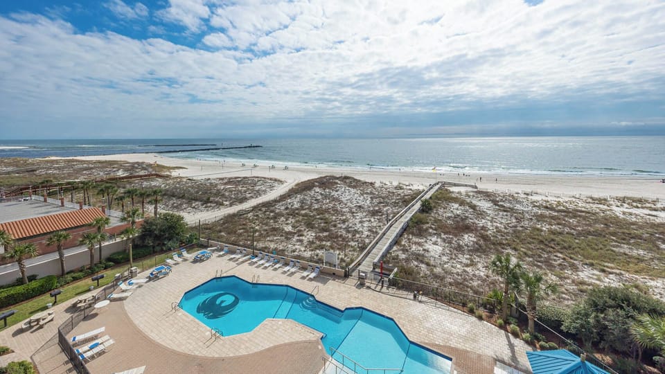 Relax by the inviting pool while enjoying views of the beach and gentle waves in the distance