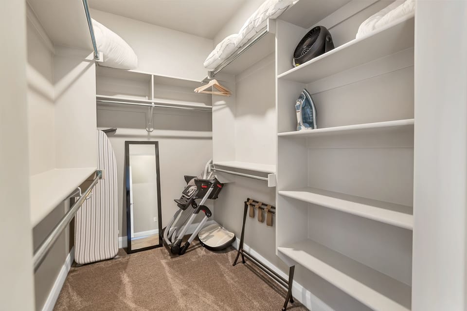 Second master suite on main level featuring a large closet with a full size mirror, playpen, iron, and a fan
