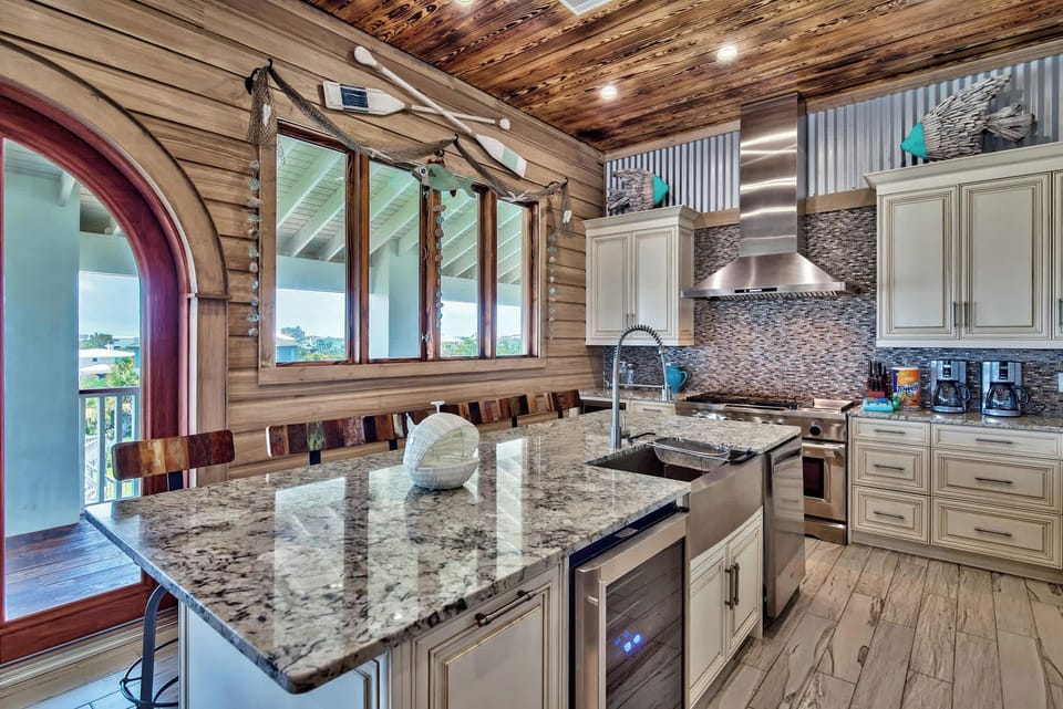 Bright kitchen angle showcasing detailed cabinetry, stone counters, and wood-beam ceilings