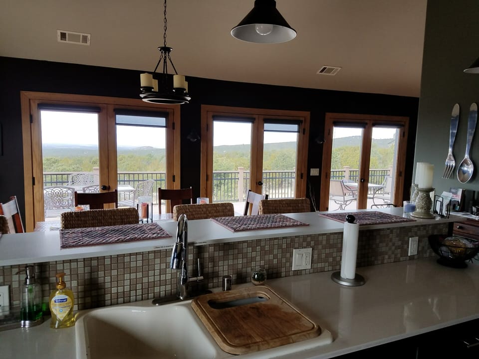 Kitchen overlooking dining room and doors open to deck outside.