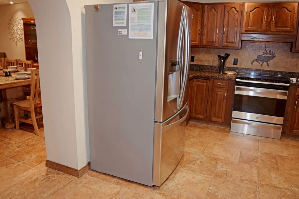Your fully equipped kitchen features stainless steel appliances, rich wood cabinetry, and granite countertops. Prepare meals with ease using modern amenities including a double oven and side-by-side refrigerator in this welcoming space.