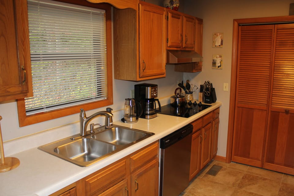 View of kitchen sink, coffee and tea pot and electric range top