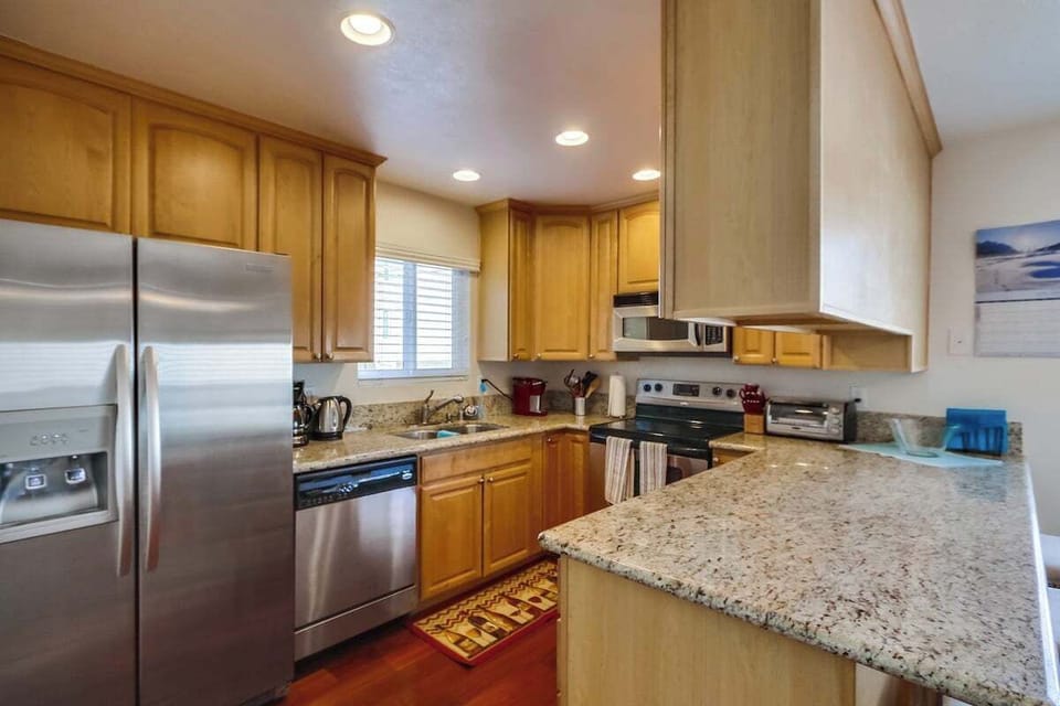 Kitchen with stainless steel appliances, granite countertops, sink, dishwasher, refrigerator, coffee maker, toaster, and blender