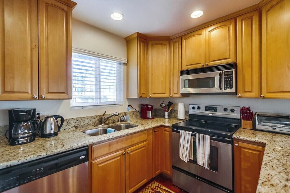 Kitchen with stainless steel appliances, granite countertops, sink, dishwasher, refrigerator, coffee maker, toaster, and blender. Everything you need to make meals at home!
