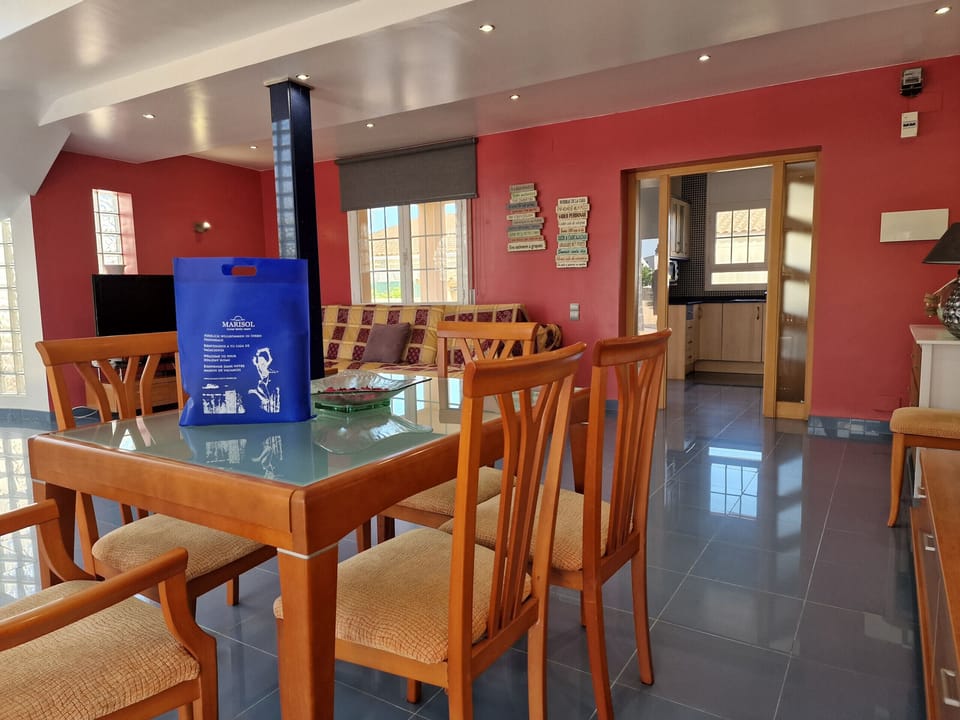 View across the entire modern living room of House Agostino, including the dining area and the adjacent, fully equipped kitchen.
