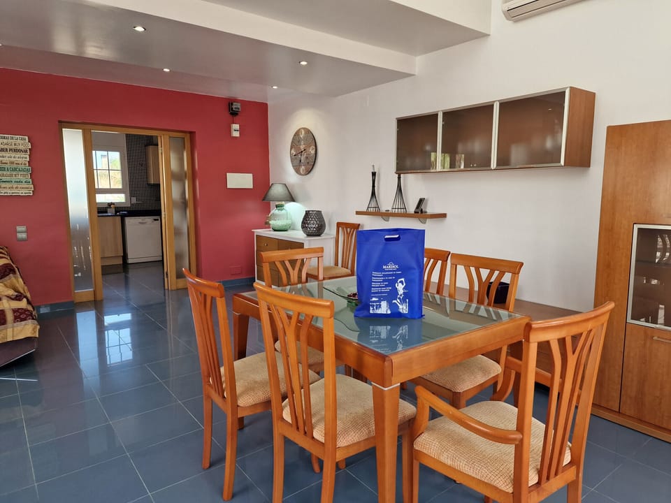 The spacious dining area in House Agostino's living room with a direct view of the entrance to the separate, modern kitchen.