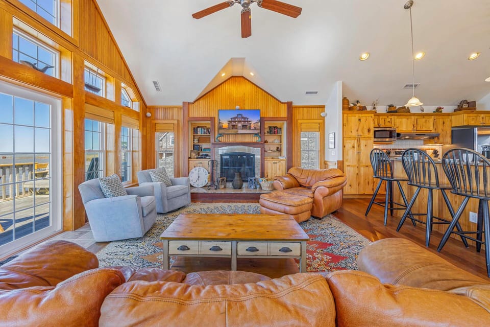 Sink into plush leather seating by your stone fireplace, where warm wood beams and panoramic windows create the perfect retreat.