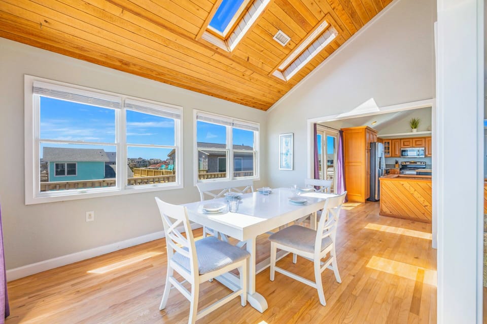Gather around this bright dining space where natural light pours through skylights and windows, creating the perfect setting for memorable meals with loved ones.