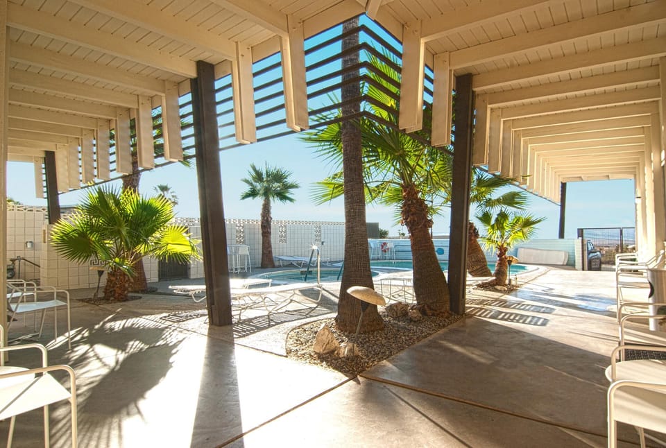 Shaded poolside walkways with patio tables and chairs