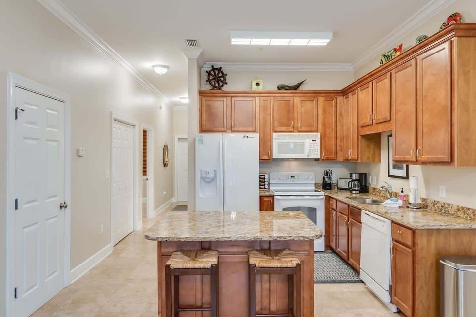 - Whip up delicious meals in this fully stocked kitchen with warm wood cabinetry & granite counters - Central island with barstools is perfect for breakfasts, snacks, or evening wine - Modern appliances, plenty of space, & charming nautical touches