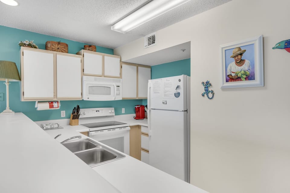 A bright kitchen with full appliances for cooking in.