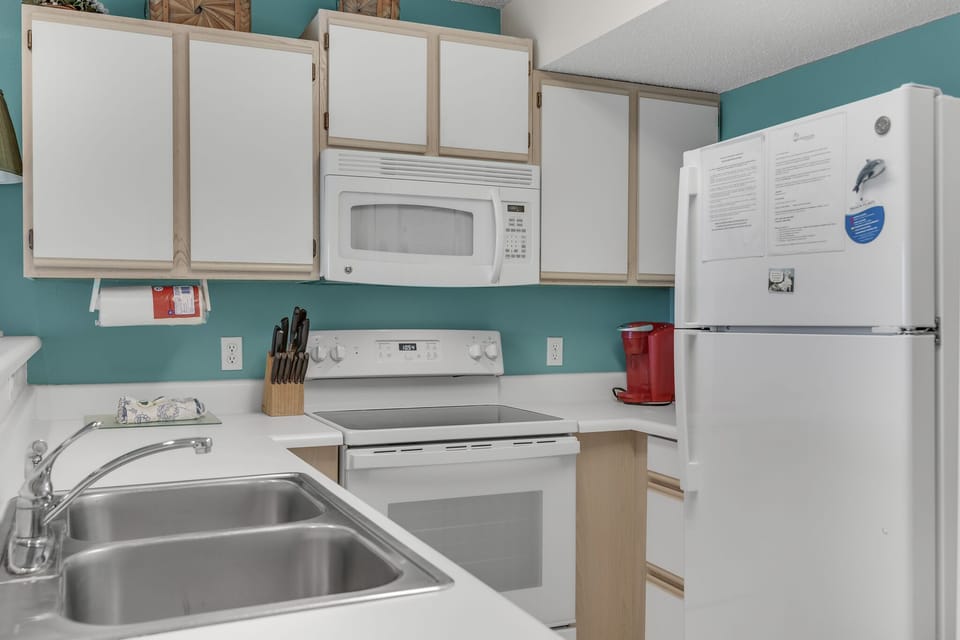 A teal-accented kitchen with a double sink and full appliances.
