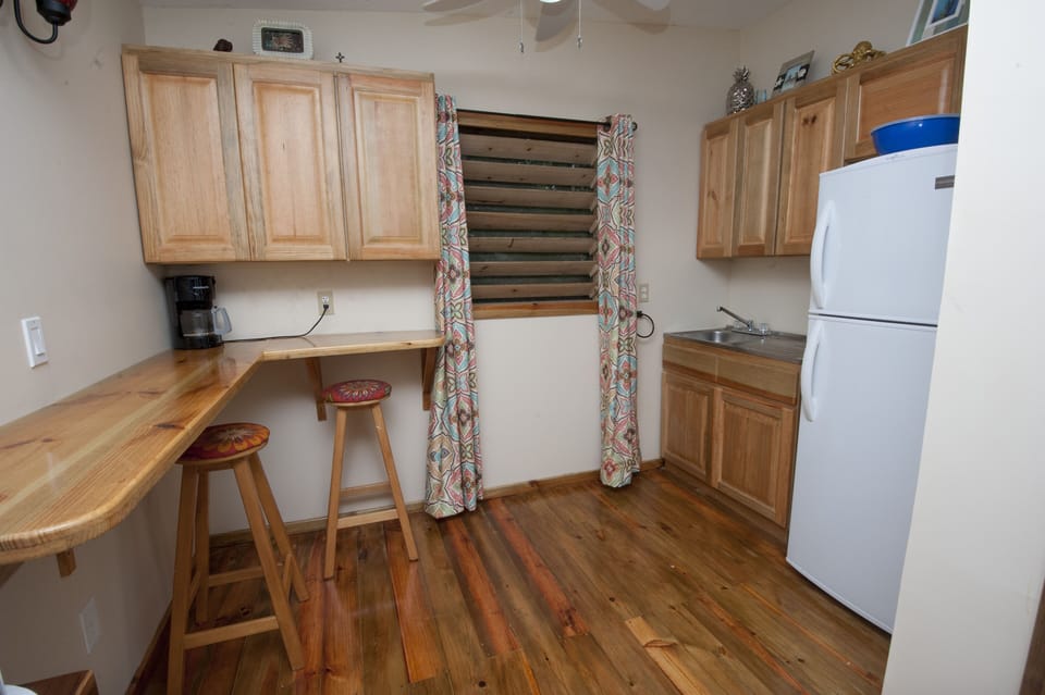 Kitchen area with refrigerator, cabinets and bar/sitting area.
