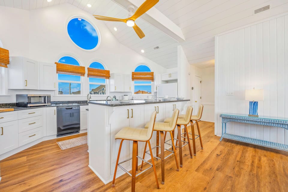 Your bright, coastal-inspired kitchen features vaulted ceilings, granite countertops, and a breakfast bar perfect for morning coffee or evening wine.