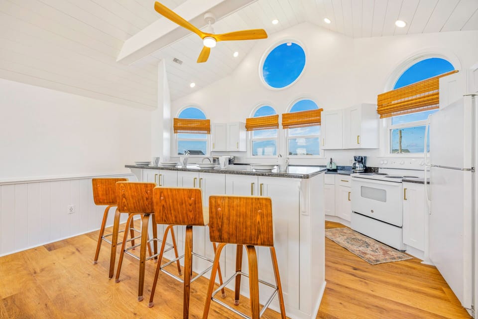 Prepare meals in your bright, fully-equipped kitchen featuring a spacious island with seating and stunning arched windows.