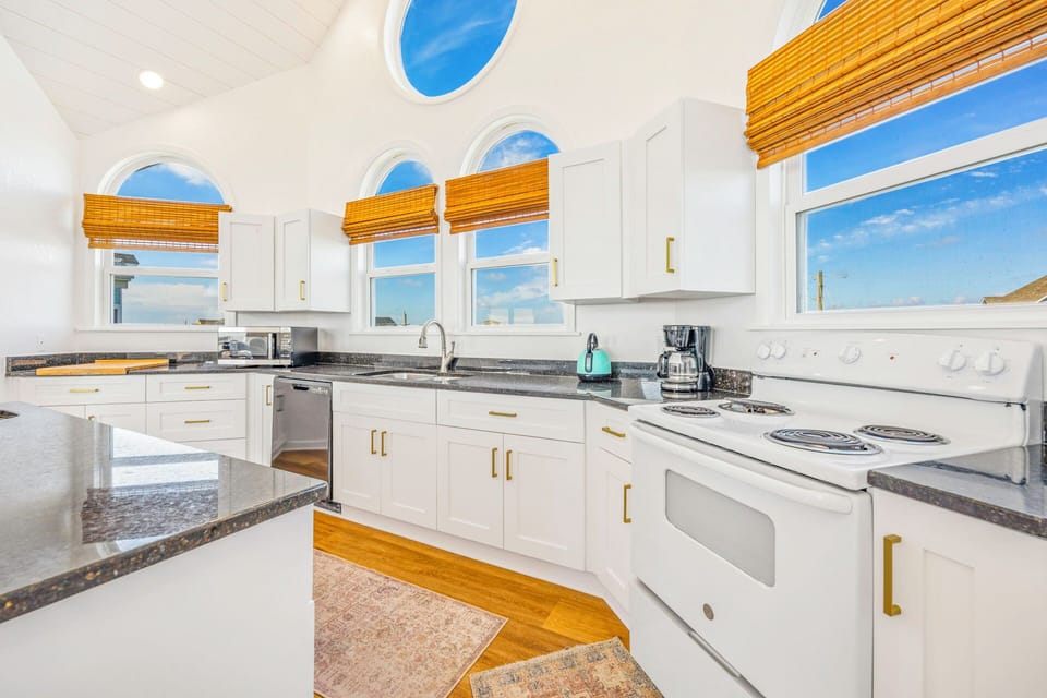 Your bright, airy kitchen awaits with granite counters, modern appliances, and stunning ocean views through elegant arched windows.