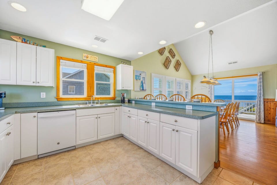 Your spacious kitchen features white cabinets, granite counters, and breakfast bar seating with stunning ocean views through the windows.