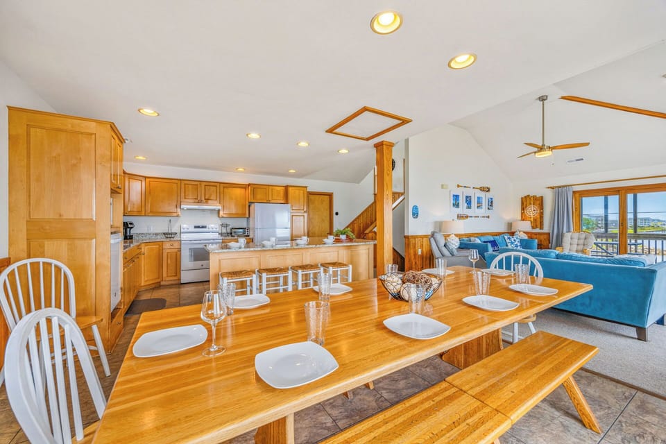 Step into your coastal retreat where golden wood tones glow under natural light. Gather around the welcoming dining table, then relax on plush seating while ocean breezes and distant views remind you you're here to unwind.