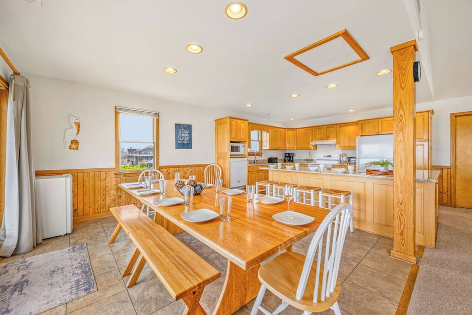 Gather around this spacious dining table for your morning coffee or a shared meal, with natural light pouring in and a fully-equipped kitchen ready for your culinary adventures.