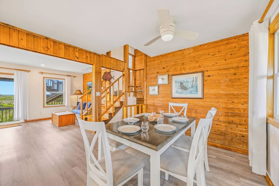 Gather around the dining table after a day exploring, warmed by rich wood walls and soft natural light from scenic windows.