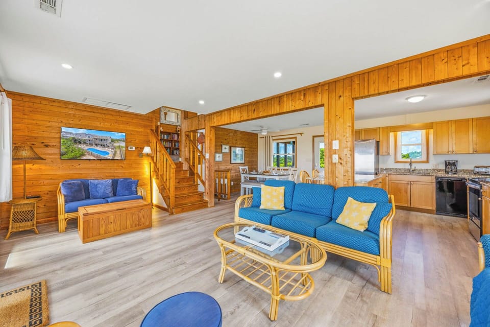 Relax in your spacious open-concept retreat, where warm wood walls meet coastal-blue seating. A fully equipped kitchen awaits your culinary adventures, while the bright living area invites memorable gatherings.