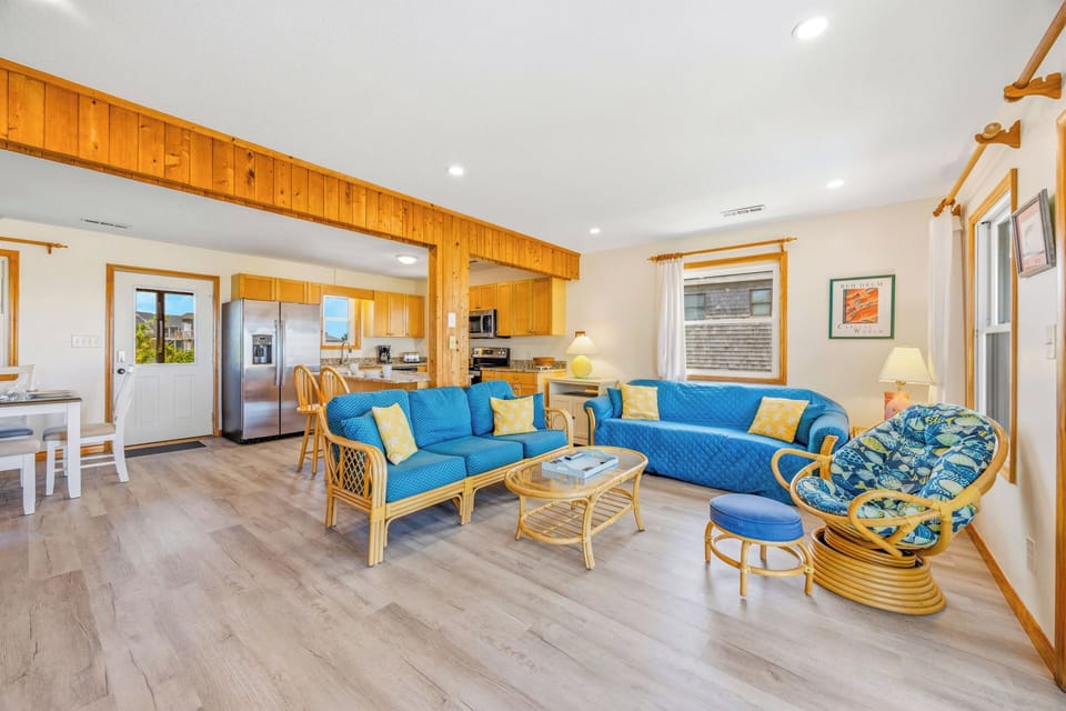 Sink into coastal comfort in this bright, open-plan living space where vibrant blue sofas and warm wood accents create a welcoming retreat for your beach getaway.