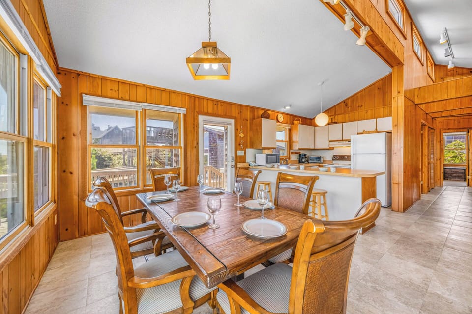 Gather around the warm wood dining table where sunlight streams through every window, setting the stage for memorable meals with your group. The open kitchen is ready for your culinary creations.