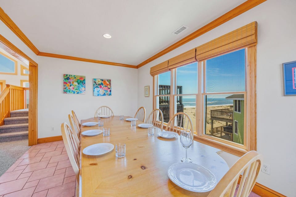 Gather around this spacious dining table where your group can share meals together while gazing out at stunning ocean and beach views through expansive windows.