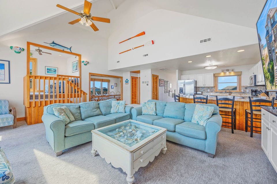 Picture yourself relaxing in this bright, airy living space with soaring vaulted ceilings, coastal charm, and ocean views from every angle—your perfect beach retreat awaits.