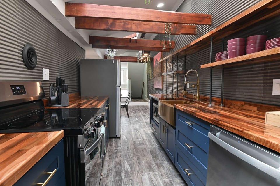 Galley-style kitchen w/ open shelving, wood counters &amp; stainless appliances throughout
