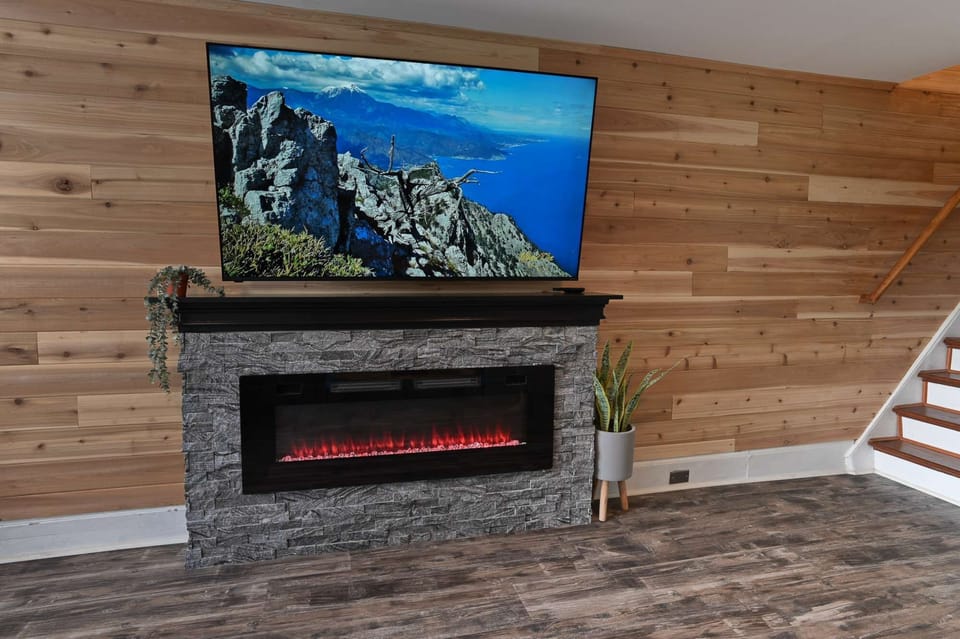 Stylish fireplace feature wall w/ mounted TV &amp; warm wood accents throughout