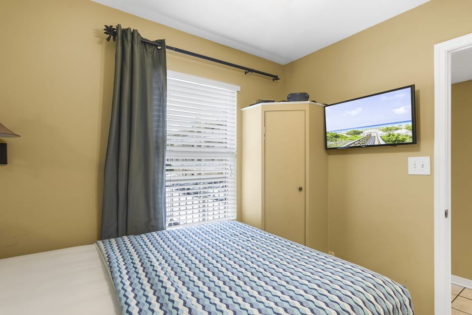 A comfortable bedroom with a smart TV and ample storage.