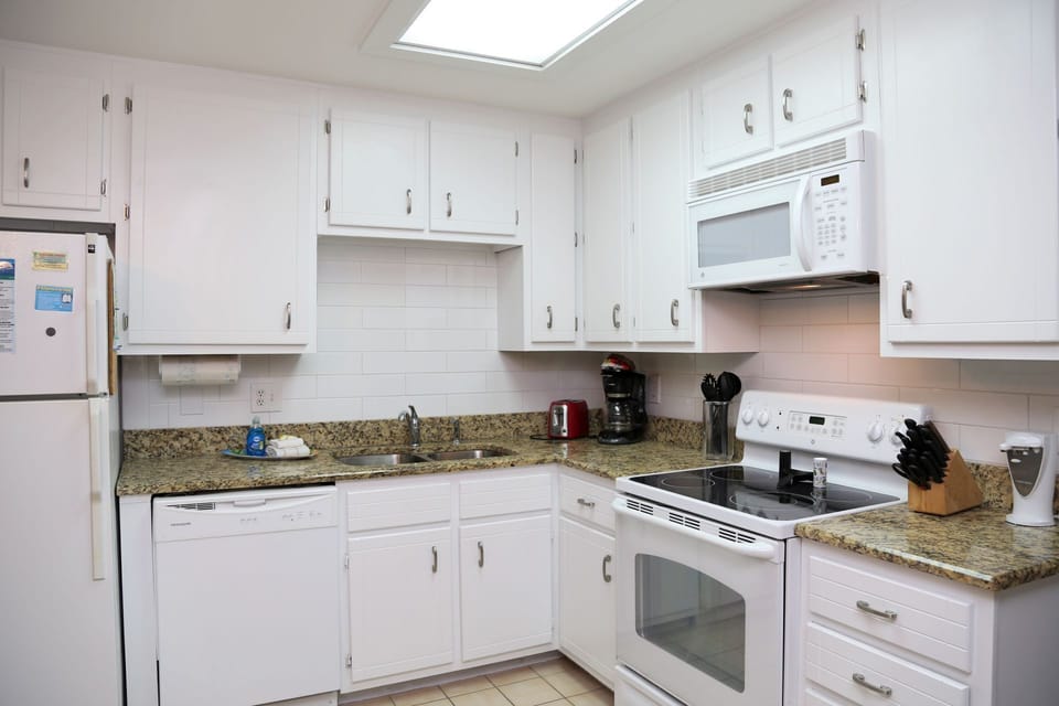 The updated kitchen includes over the counter microwave, modern backsplash, and plenty of counter space for prepping meals.